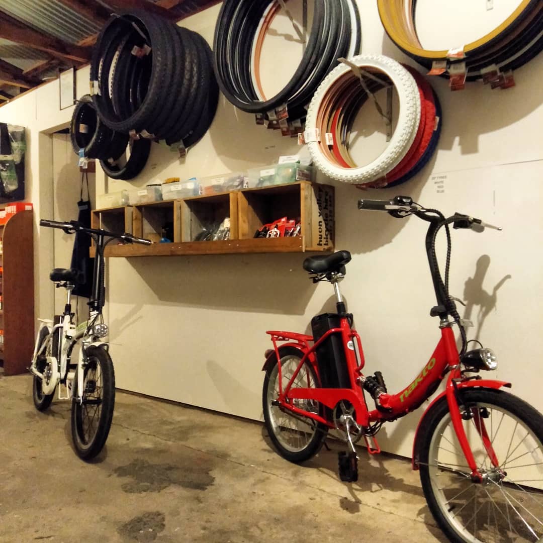 Coils of tyres in white, red, tan and black hung on the wall above two folding electric bikes